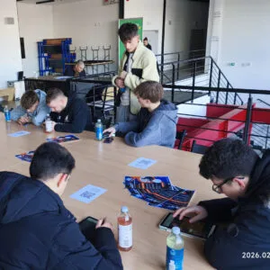 Mladí ľudia pri stole pracujú v skupine s kartami a tabletmi